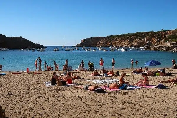 Sunbathers on Cala Vadella, Ibiza best beach destinations for solo travelers