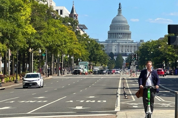 Man on electric scooter Pennsylvania Avenue with Capitol Building